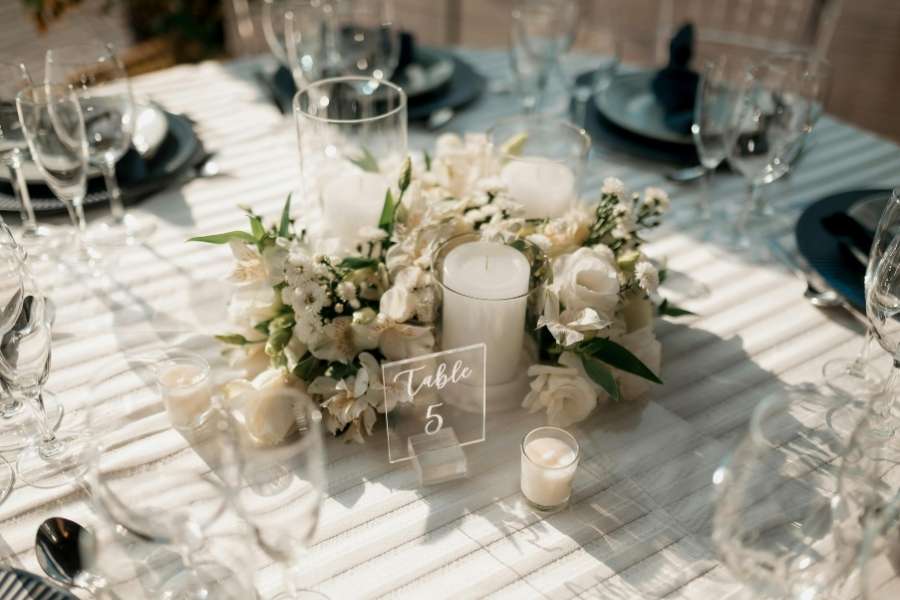 Décoration de table de mariage élégante avec un centre de table floral blanc, des bougies et un numéro de table transparent.