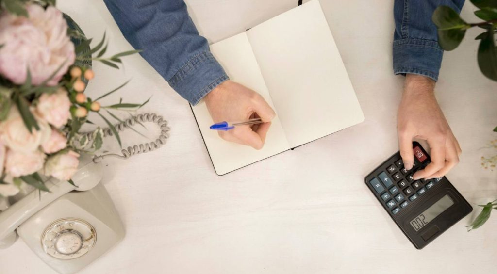 Calcul manuel des dépenses sur un carnet avant de passer à une application gratuite organisation mariage.